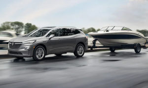 A silver 2024 Buick Enclave towing a boat down a road near Carmel, Indiana