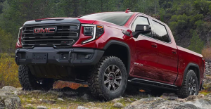 A red 2025 GMC Sierra 1500 driving over a rocky surface near Carmel, Indiana