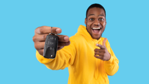 A person showing the keys to their new car to the camera in front of a blue background near Carmel, Indiana